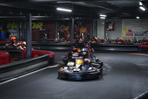 Vedere de ansamblu a circuitului indoor Red Motor, cu borduri roșii și un kart în viraj