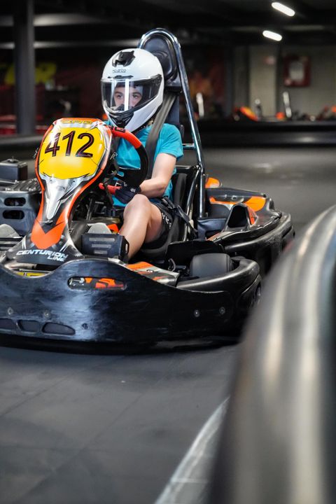Copil cu cască albă pilotând un kart cu numărul 412 pe circuitul indoor Red Motor